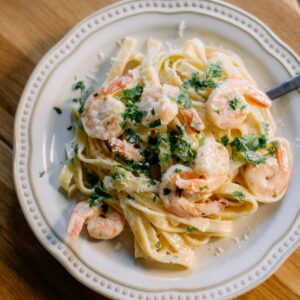 A plate of pasta with shrimp and parsley.